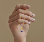 Elegant birthstone jewelry featuring a vivid blue sapphire, suspended on a delicate gold chain designed for layering or solo wear.